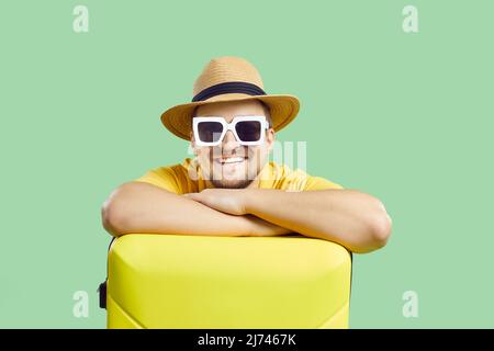 Happy man with suitcase who is waiting for summer trip isolated on light green background. Stock Photo