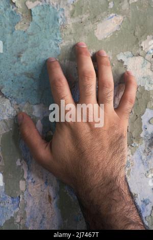 Close up of man's hand touching peeled wall paint Stock Photo