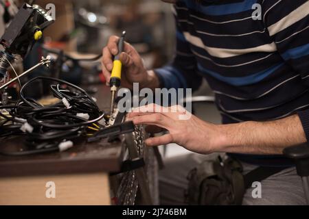 Industrial worker man soldering cables of manufacturing equipment in a factory. Selective focus Stock Photo