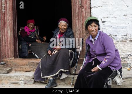 Three Tibetan ladies sit in front of a Buddhist Temple in SIchuan province Stock Photo