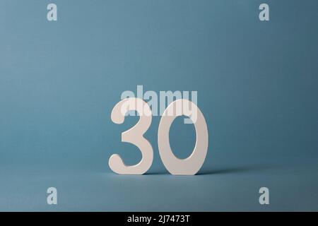 White wooden number thirty 30 on blue background. Stock Photo