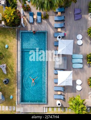 Drone aerial view from abotve at pool,Praslin Seychelles ,couple men and women in pool during vacation at a luxury resort at the beach of Anse Volbert tropical island with withe beaches and palm trees