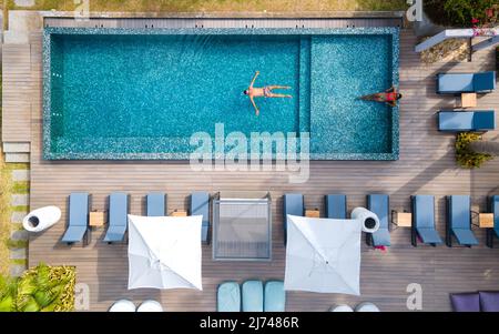 Drone aerial view from abotve at pool,Praslin Seychelles ,couple men and women in pool during vacation at a luxury resort at the beach of Anse Volbert tropical island with withe beaches and palm trees