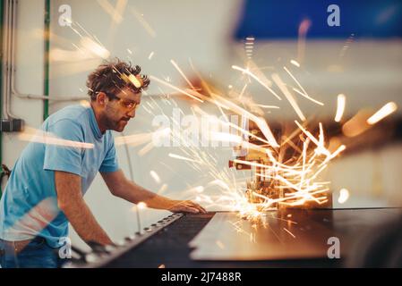 Within heavy industry. A man works in a modern factory on a CNC machine. Selective focus Stock Photo