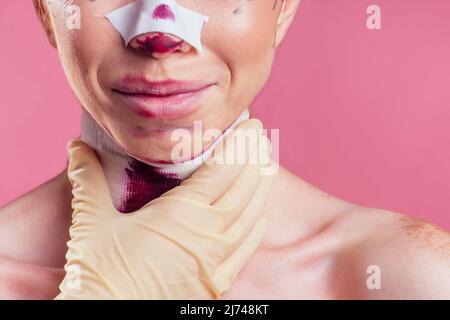 Patient in bandages. Nurses and young woman in studio pink background Stock Photo