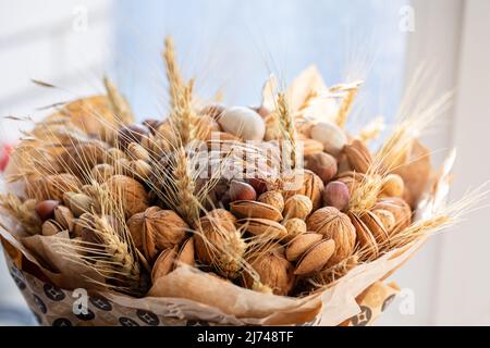 Handmade bouquet of nuts, pine cones, spikelets for holiday. Food floristry. Gift for men. Edible bouquet for birthday, valentine's day. Selective focus. High quality photo Stock Photo