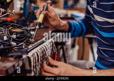 Industrial worker man soldering cables of manufacturing equipment in a factory. Selective focus Stock Photo