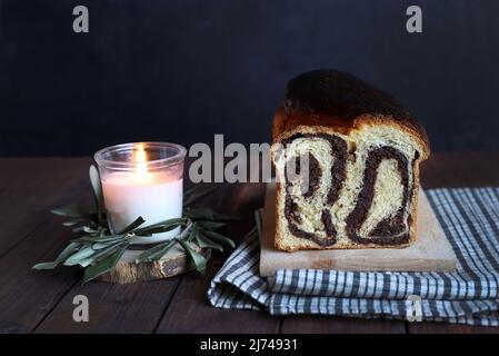 Cozonac - homemade traditional sweet bread for Easter and burning candle on dark background. Romanian food. Concept of Easter. Stock Photo