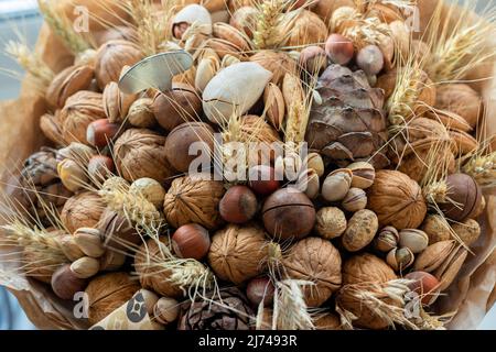 Handmade bouquet of nuts, pine cones, spikelets for holiday. Food floristry. Gift for men. Edible bouquet for birthday, valentine's day. Top view, selective focus. High quality photo Stock Photo