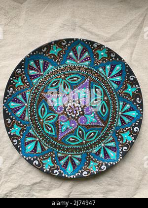Decorative ceramic plate with  different colors. painted plate on white background, closeup, top view. Decorative porcelain plate painted with acrylic Stock Photo