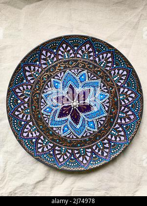 Decorative ceramic plate with  different colors. painted plate on white background, closeup, top view. Decorative porcelain plate painted with acrylic Stock Photo