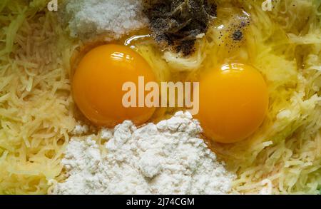Broken chicken eggs and grated potatoes, salt, pepper, flour. food, potato pancakes, dish Stock Photo