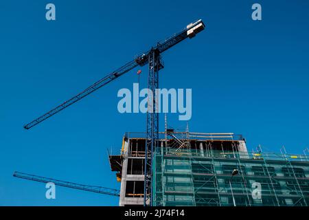 Unfinished building and tower crane on sky background. Stock Photo