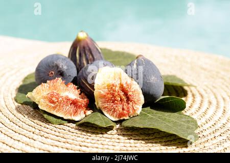 Opened black fig on a green leaf with other figs Stock Photo