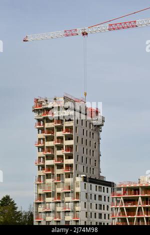 Basel, Switzerland - April 2022: Tower crane working on the contruction of a new apartment building Stock Photo