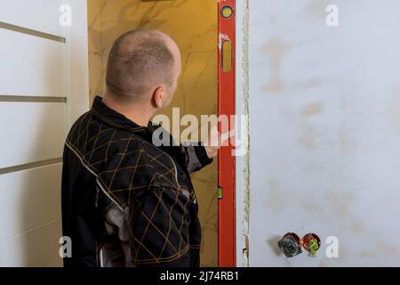 Carpenter worker installation process of checks level correctness installation wood door Stock Photo