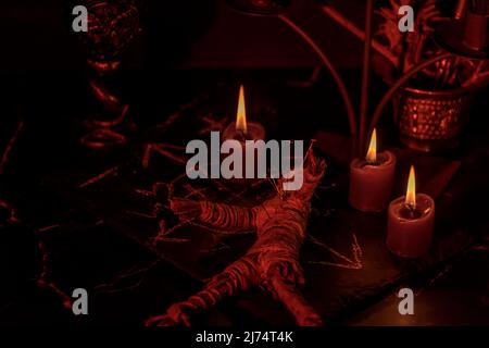 Voodoo Magic concept. Voodoo doll studded with needles with pierced rag heart on pentagram and around burning candles. Spooky or eerie magical Stock Photo