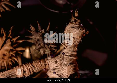 Voodoo Magic concept. Voodoo doll studded with needles with pierced rag heart on pentagram and around burning candles. Spooky or eerie magical Stock Photo