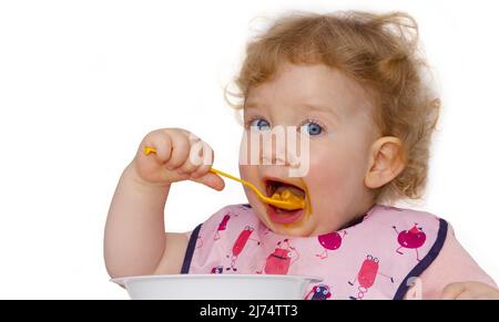 Toddler eats on his own Stock Photo