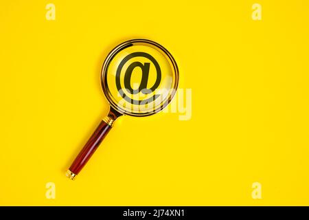 Dog sign is an email symbol under magnifying glass on yellow background Stock Photo