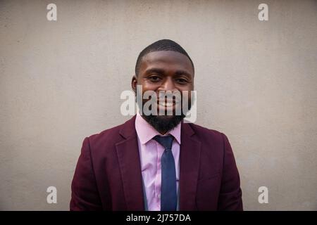 portrait of a smiling young african businessman isolated on beige background Stock Photo