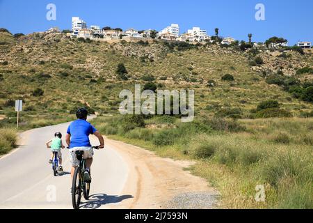 Santa Pola, Alicante, Spain- May 6, 2022: Cyclist riding along the road that borders little beaches of the Lighthouse in Santa Pola, Alicante Stock Photo