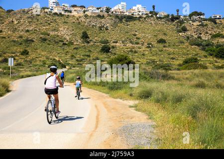 Santa Pola, Alicante, Spain- May 6, 2022: Cyclist riding along the road that borders little beaches of the Lighthouse in Santa Pola, Alicante Stock Photo