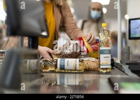 Cropped view of young woman shopping in supermarket, putting products on checking desk Stock Photo