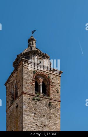 The bell tower of the ancient Pieve di San Giovanni Battista, Buti, Pisa, Italy, with an airplane leaving its trail in the background Stock Photo