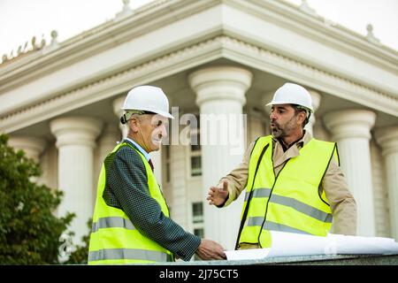 Two senior construction workers are having a conversation about the plans Stock Photo