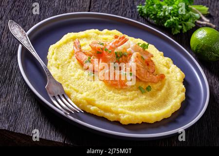 Polenta e schie fritte, venetian dish, polenta with fried shrimps on a plate on dark wood table with parsley and lime on background, horizontal view f Stock Photo
