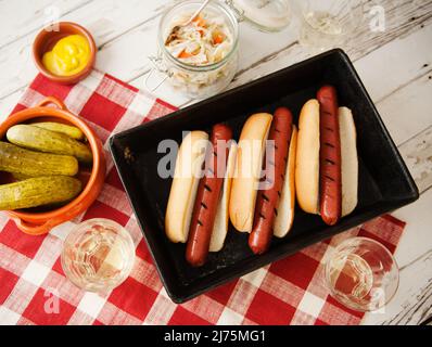 Three Grilled Hotdogs with Pickles and Cole Slaw on a White Picnic Table; From Above Stock Photo