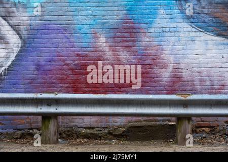 Painted brick wall and metal guard rail in Midwest city back alley. Stock Photo