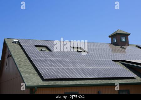 Solar panel installation on a nice barn style house with sunny blue skies in the background Stock Photo