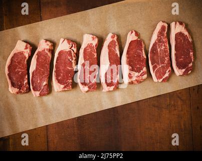 Raw Grass Fed New York Strip Steaks on Parchment Paper Stock Photo