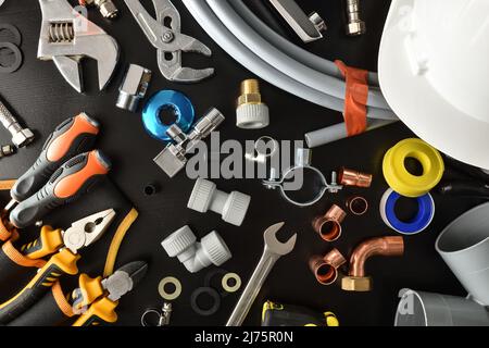 Sample of plumbing materials and tools on black workbench. Top view. Horizontal composition. Stock Photo