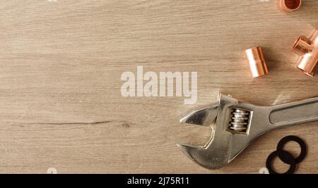 Plumbing conceptual background with wrench and metal pipes on wooden table. Top view. Horizontal composition. Stock Photo