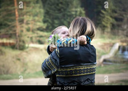 Mom hugs her son after a gift of a bouquet of flowers from him Stock Photo