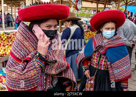 Young Indigenous Quechua Women Using Mobile Phones At The Famous Sunday Market In The Village Of Chinchero, The Sacred Valley, Urubamba Province, Peru Stock Photo