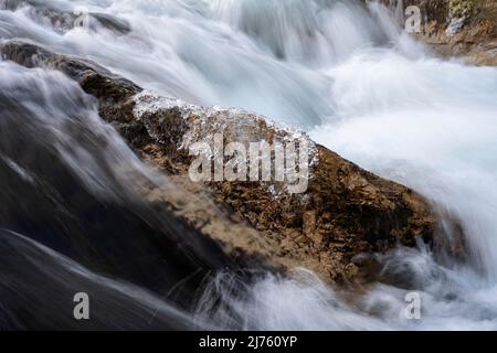 Clear ice in winter on a stone in the current at the Rissbach in the so called Eng in Tirol in the Karwendel mountains with clear water and strong current Stock Photo