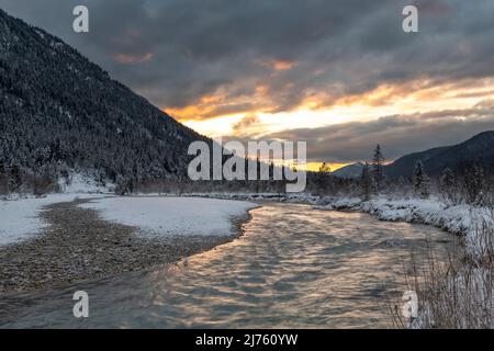 Dense clouds during sunset in the Isar meadows near Wallgau in the Karwendel, with the creek bed / river course in the foreground Stock Photo