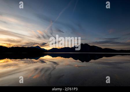 Simetsberg unfolds angel wings reflected in the water of Walchensee at sunset. Cloud formation in the shape of a wing. Stock Photo