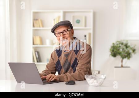 Smiling elderly man sitting at home and using a laptop computer Stock Photo