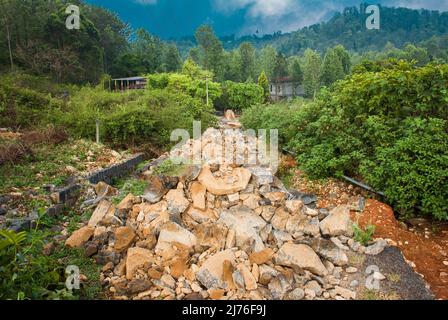 Rocks laid down to construct foundation for the new road in hilly region. Construction work in mountain area. Stock Photo