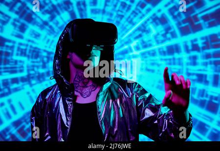 Serious young man in reflective coat wearing virtual reality device analyzing virtual space through tactile perception Stock Photo