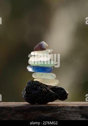 closeup view of sea glass pebbles and a tiny seashell balances on a lava stone Stock Photo