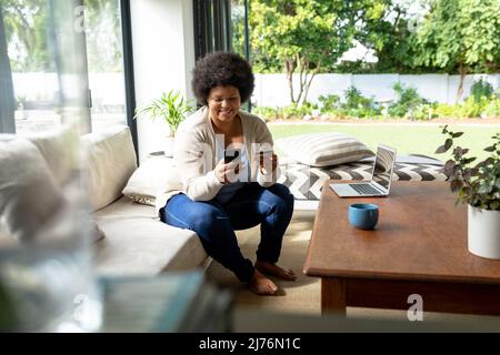 African american mid adult woman using smart phone while doing online shopping Stock Photo