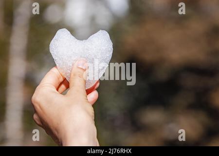 Hand holding heart made of snow close-up Stock Photo