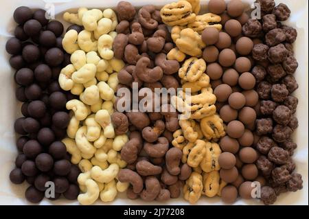 Six types of chocolate covered nuts in vertical rows. Stock Photo