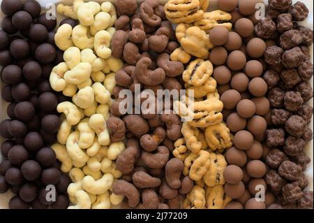 Six types of chocolate covered nuts in vertical rows. Stock Photo